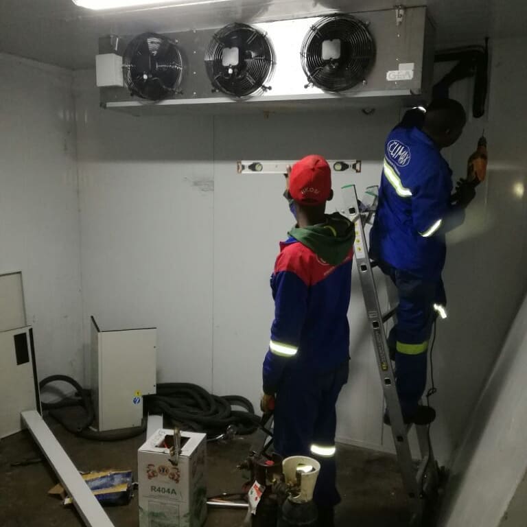 Worker assembling insulated cold room panels with electrical control box mounted