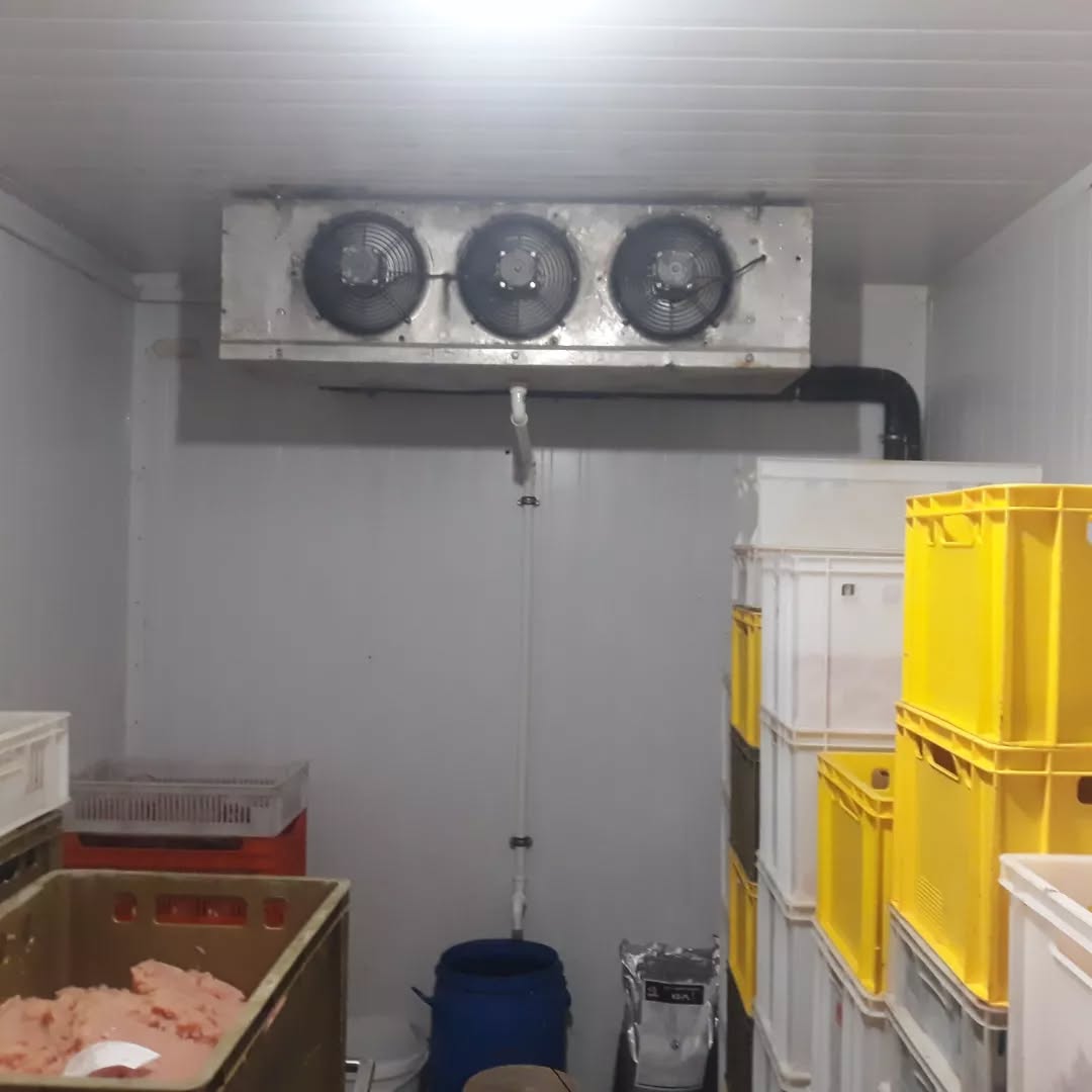 Technician installing an evaporator unit inside a new cold room