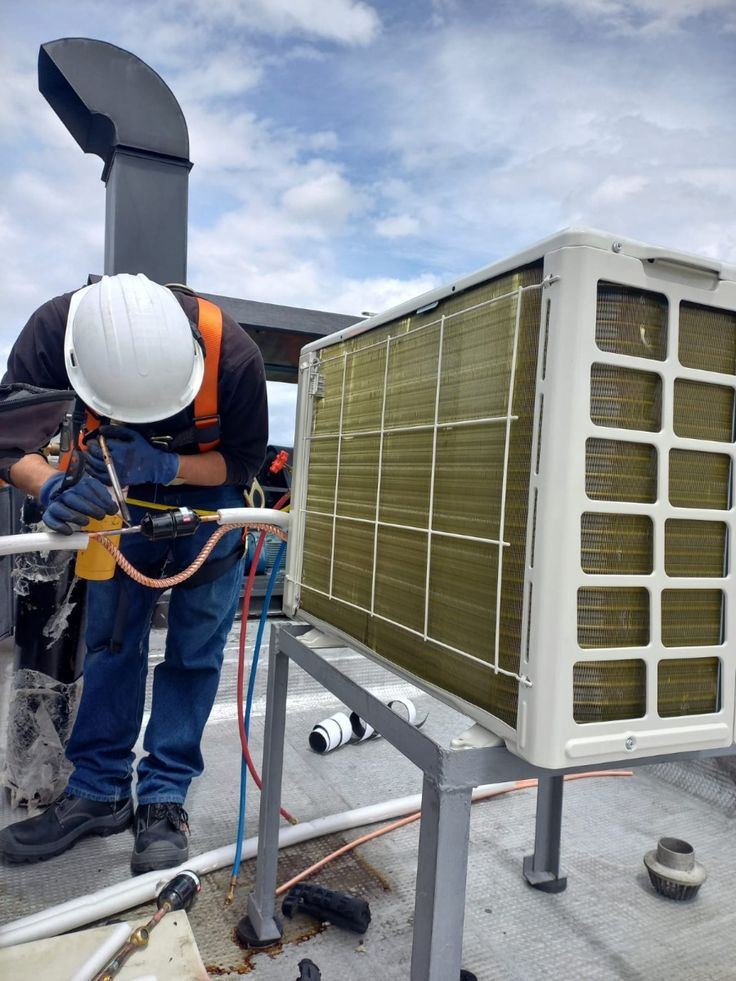 Technicians on an elevated platform servicing a warehouse exhaust unit